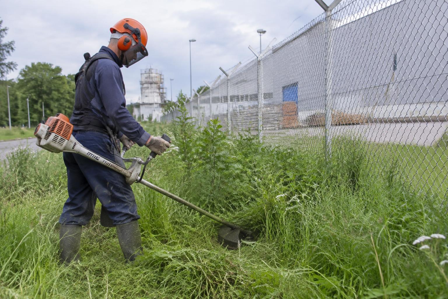 Trabajador realizando desmalezado junto a un cerco industrial
